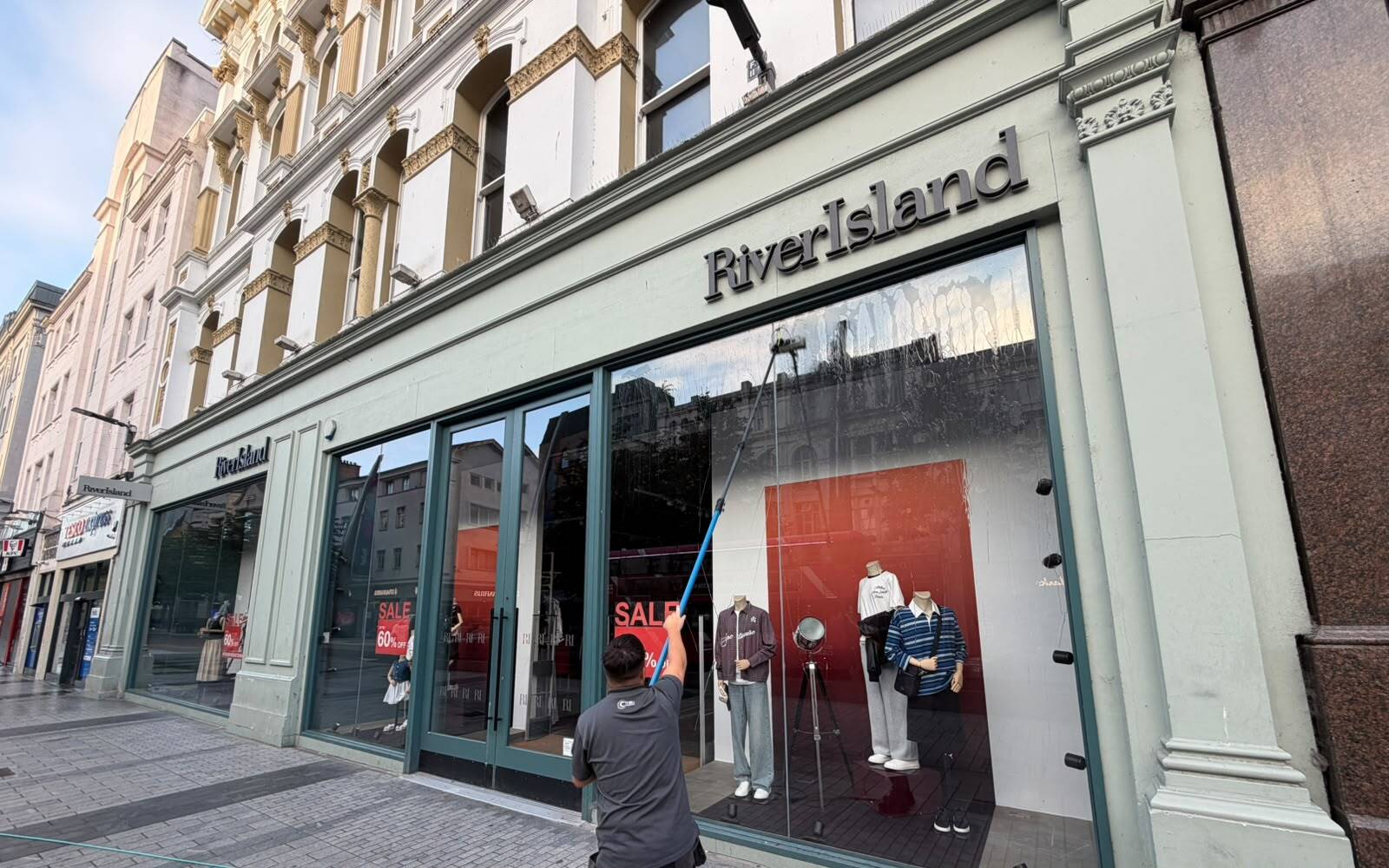 Window cleaner cleaning windows in Belfast City Centre